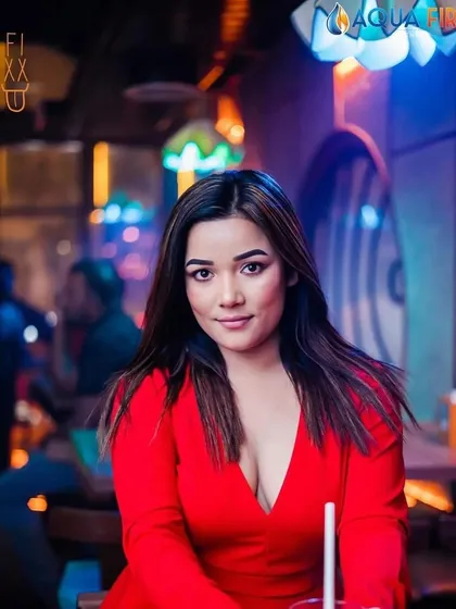 A guest looking radiant in red at The Fixx Bar. The lighting and decor make everyone look and feel their best.