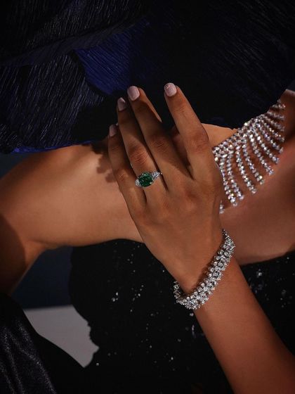 A detailed shot of the hand, showcasing an emerald ring and diamond bracelet from Purab Paschim's "Luminance" collection.