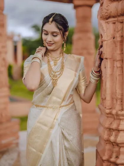 A candid and graceful portrait of the bride adjusting her earring, capturing a natural and delicate moment.