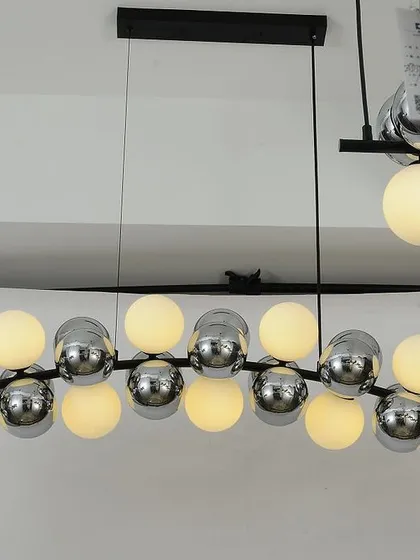 A linear chandelier featuring a mix of frosted and chrome-finished globes. This is a great option for lighting a dining table or kitchen island.