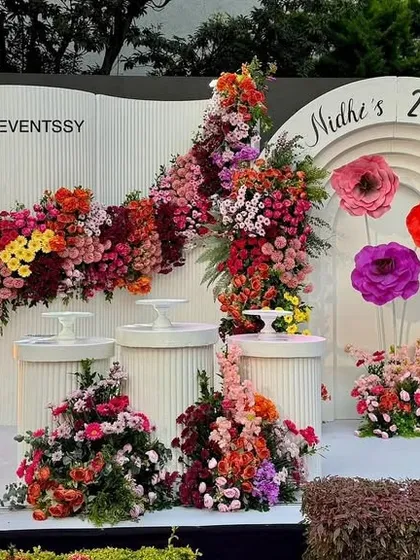 Celebrating a 25th birthday in style with a sophisticated floral wall, combining a vibrant mix of fresh and paper flowers with elegant marquee lights for a chic milestone event.