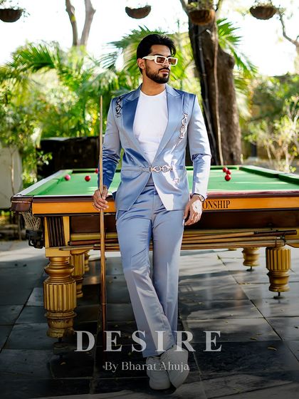 A full-length shot of the light blue suit, showing how it creates a striking silhouette against the backdrop of a pool table. This is luxury with a playful side.