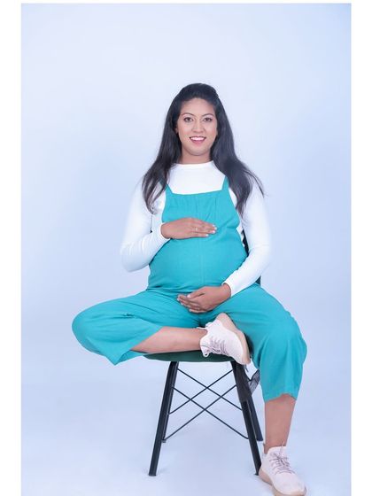 A relaxed and casual studio portrait of a mother-to-be. Her comfortable jumpsuit and happy smile create a modern and approachable vibe for her maternity photos.