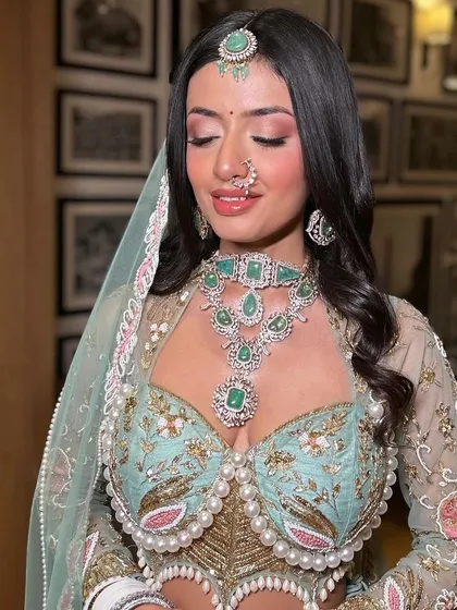 A close-up of this fresh day bridal look. The pink eyeshadow and glossy lips perfectly complement the pastel outfit and emerald jewelry.