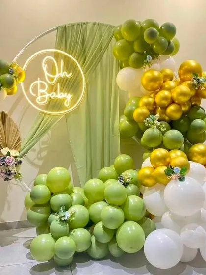 An elegant and modern 'Oh Baby' shower backdrop. This setup uses a beautiful color palette of sage green, gold, and white, with a circular frame, a custom neon sign, and delicate floral accents.