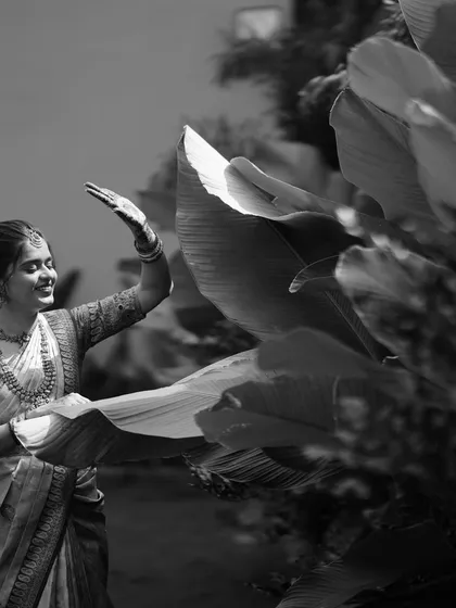 There is a timeless elegance to black and white photography. This candid moment from an engagement session, where she interacts gently with nature, feels poetic and real. It highlights our ability to find and capture serene, beautiful moments amidst the celebration.