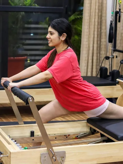 A client enjoys a deep stretch in a split variation on the Reformer. This is a great example of how we help you transform your body and increase flexibility.