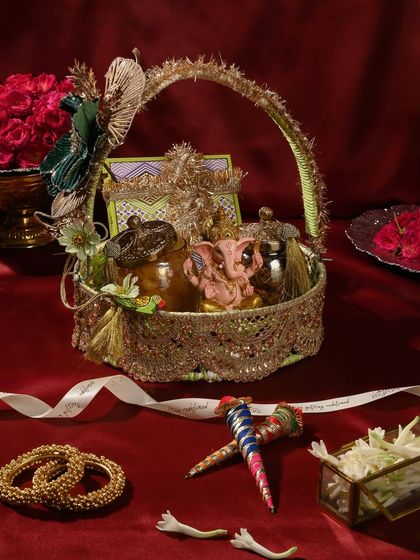This ornate basket, featuring a small Ganesha idol, is also perfect for Teej or any auspicious occasion. It's filled with treats and decorated with traditional elements.