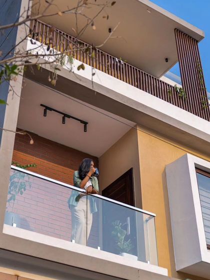 A detail shot of the balconies at the Sarjapur residence. The glass railings ensure unobstructed views, while the vertical louvers provide privacy and shade, adding a layer of texture to the facade.
