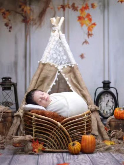 An autumn-inspired rustic photoshoot. The warm colors of the fall leaves, combined with a miniature teepee and vintage props, create a wonderfully cozy atmosphere.