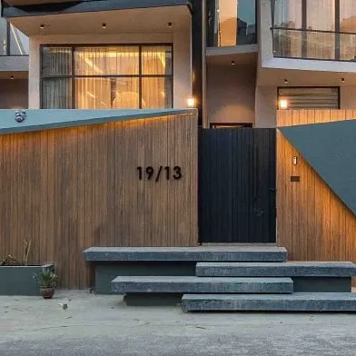 The entrance of Casa Acentuada, featuring floating stone steps and a custom house number integrated into the angular wall design.