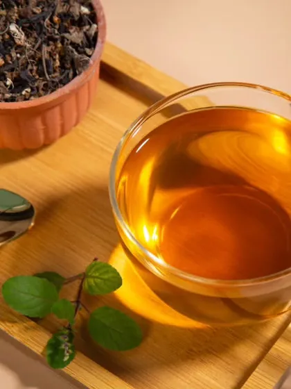A styled shot for a tea brand, featuring a clear cup of ginger tea on a bamboo tray. The warm lighting and simple props create an inviting image for beverage photography.