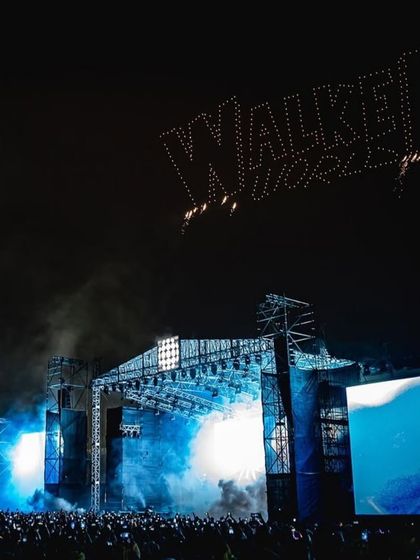 The 'WALKER' name spelled out in the night sky by our drone fleet, hovering over the massive concert stage.
