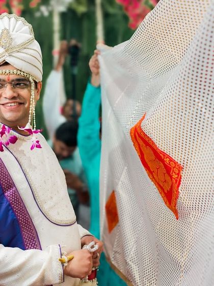 The groom's happy expression as he awaits his bride during the Antarpat ritual in a Maharashtrian wedding.