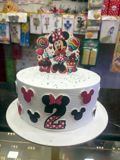 For a 2nd birthday, this Minnie Mouse cake is decorated with her signature bow and silhouette. The clean lines and striped pattern give it a modern and stylish look.