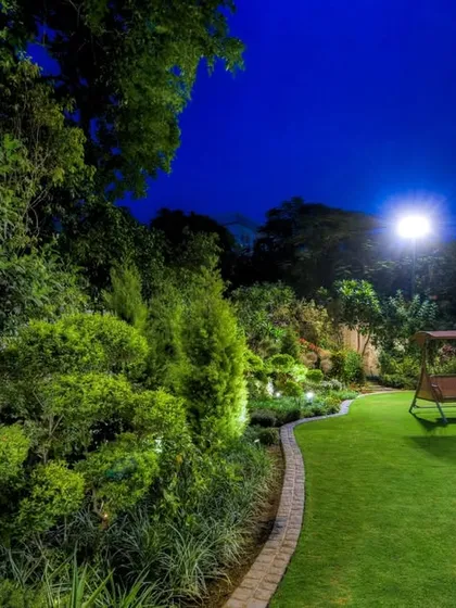 A tranquil night scene in a residential garden, where soft moonlight and subtle landscape lighting illuminate a peaceful lawn and a classic garden swing. This demonstrates our ability to create a serene and secure atmosphere after dark.