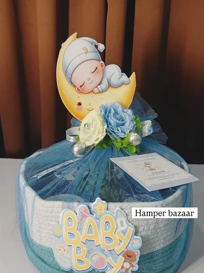 A close-up of the 'Baby Boy' hamper in a woven basket, topped with a cute cutout and delicate flowers.