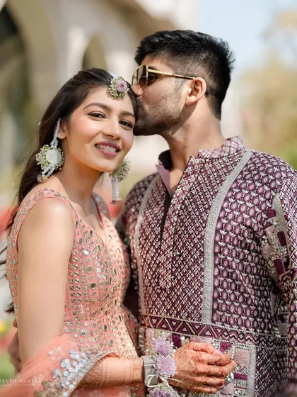 A tender kiss on the forehead. I styled this couple in complementary outfits, with her peach lehenga and his patterned kurta creating a chic and modern look for their sun-drenched haldi ceremony.