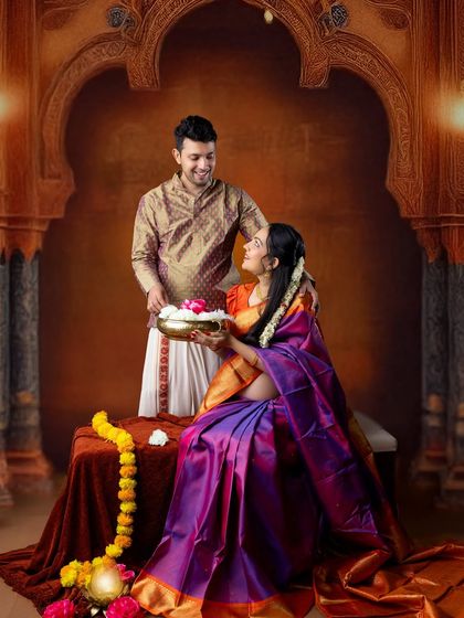 A fine-art maternity portrait with a festive feel. The couple is dressed in beautiful traditional wear, creating a rich and celebratory image.