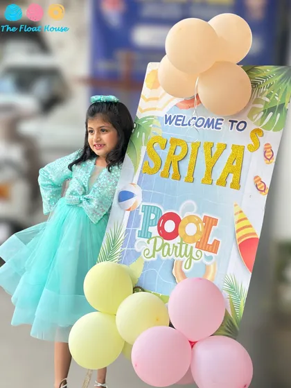 The birthday girl, Sriya, posing with her personalized welcome stand for her pool party. We ensure every detail, from the decor to the welcome, makes the day feel extra special.