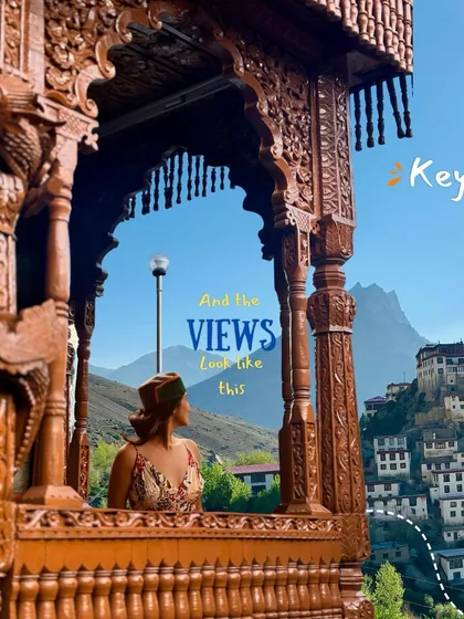 A traveler enjoying the view of Key Monastery from a window with traditional wooden architecture. These are the quiet, picture-perfect moments you find in Spiti.