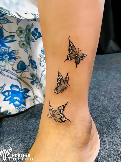 A trio of delicate butterflies fluttering up the ankle. This fine-line tattoo is a graceful symbol of change and beauty.