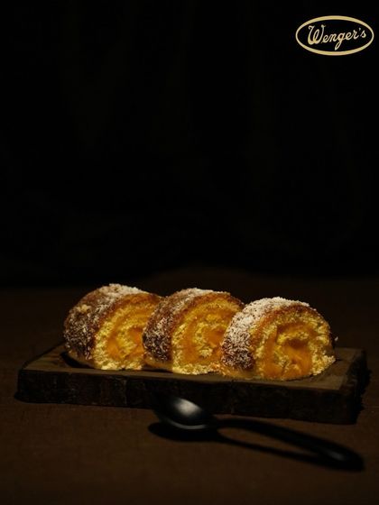 A Lemon Swiss Roll, offering a lighter, tangier alternative. The zesty lemon cream is rolled into a soft sponge and dusted with coconut.