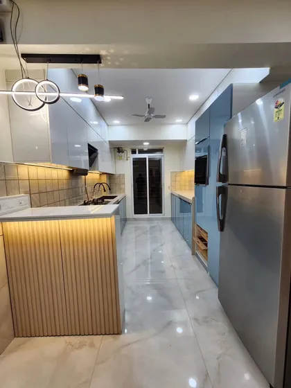 A complete view of the modern parallel kitchen, with the refrigerator on one end and a breakfast bar on the other.