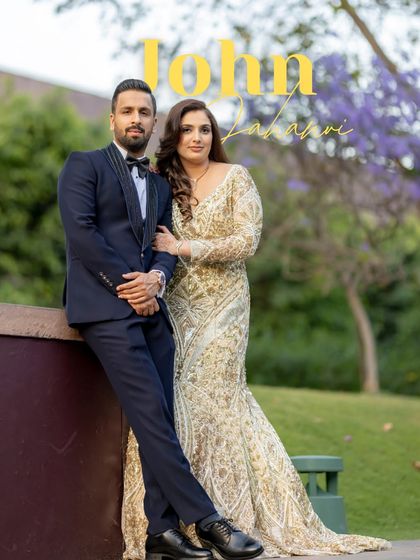 A stylish, posed portrait of John and Jahanvi. Leaning against a wall with lush purple flowers in the background, they exude confidence and modern elegance.