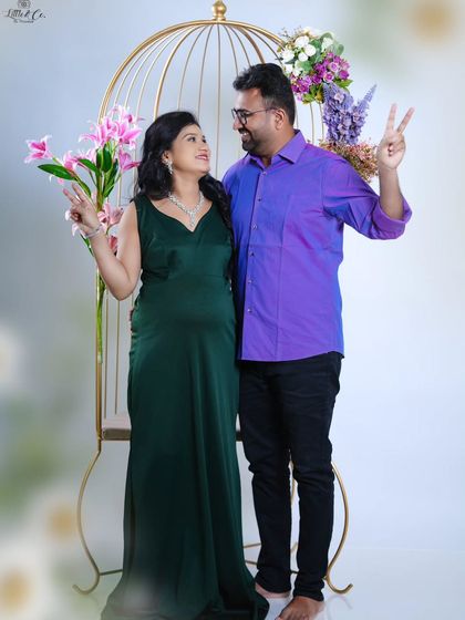 A fun and cheerful pose from the same session. The couple's playful peace signs add a touch of their personality to this classic studio maternity shoot.