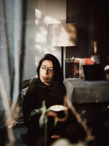 A friend seen through a window, surrounded by the soft clutter of her creative life. These layers add so much depth and personality to a portrait.