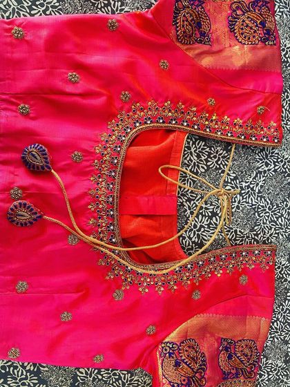 A bright pink blouse with a contrasting printed fabric border on the sleeves. The neckline is embroidered with gold thread and small beads.