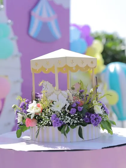 A beautiful miniature carousel centerpiece filled with fresh purple and pink flowers. This elegant detail adds a touch of sophistication to the whimsical carnival theme.