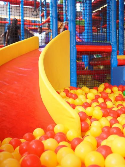 A bright red slide ready for action, ending in a sea of colorful balls. Our slides are a highlight for many kids, offering a thrilling ride every time.