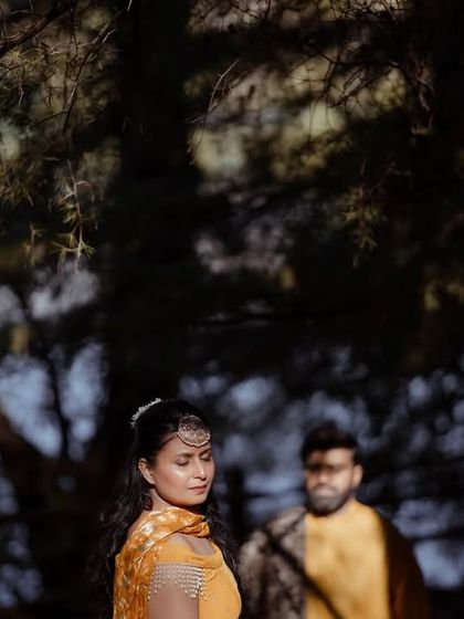 A beautiful, softly lit portrait of the bride, framed by the dark leaves of a tree, creating a sense of intimacy and focus.