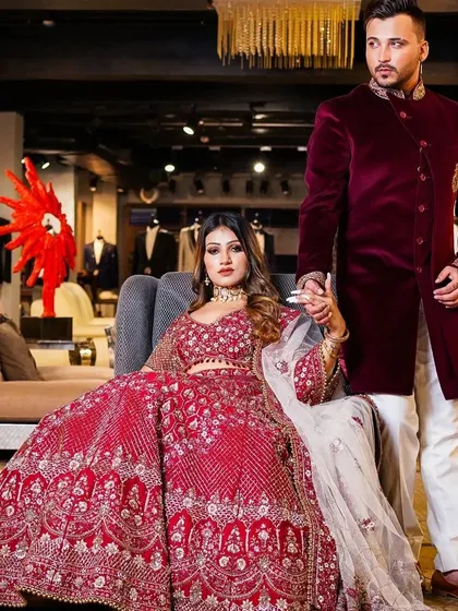A powerful shot for a luxury bridal campaign, featuring a couple in coordinated couture. The composition places the bride in a position of regal elegance, while the groom's protective stance adds a narrative element to this opulent fashion photograph.