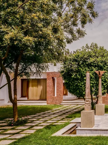 The garden at the House of Axes features ancient stone columns that act as visual anchors, creating a dialogue between the new structure and the layered history of the site.