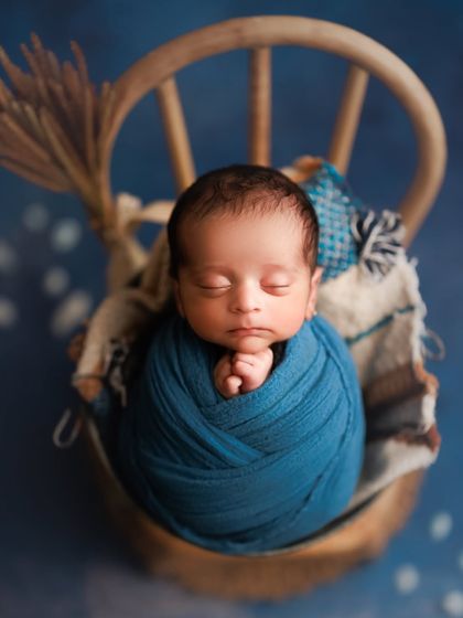 The deep, royal blue of this wrap creates a striking and beautiful portrait. The simple setup in a bucket chair allows the rich color and the baby's peaceful face to be the stars.