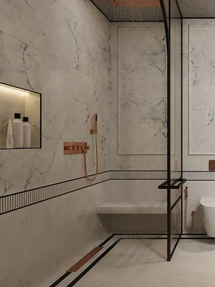 Inside the shower, a built-in marble bench and a niche for toiletries are accented with warm, rose-gold fixtures, adding a touch of luxury.