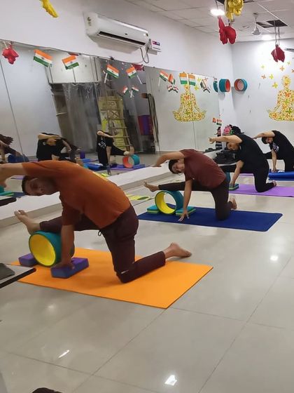 Here, we are using yoga wheels and blocks to assist with a deep lunge and side stretch. This combination of props helps to improve hip flexibility and lengthen the side body while maintaining stability.