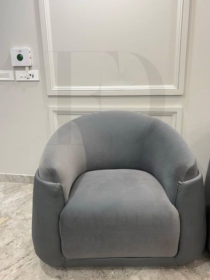 A pair of modern, curved armchairs in a two-tone grey upholstery. The design offers a comfortable, enveloping feel, perfect for creating an intimate conversation nook.