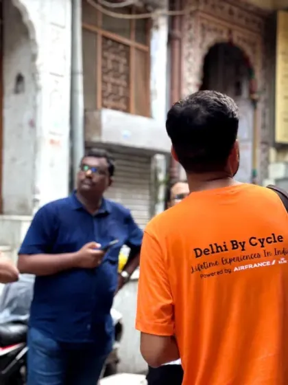 A guide in our signature orange shirt points out architectural details to an engaged group in an Old Delhi alley.