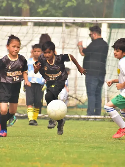 A young player from the Golden League in full flight, dribbling the ball with speed and control.