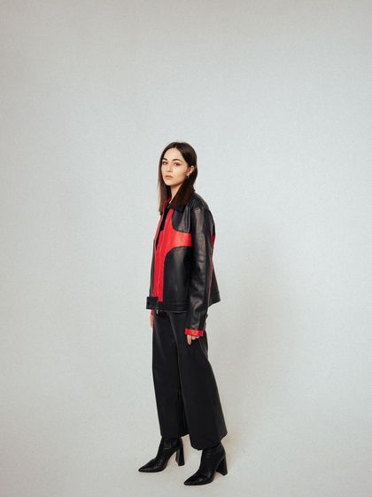 A full-length profile shot, showing the jacket's silhouette and how it pairs with the rest of the outfit. The clean background keeps the focus on the fashion.