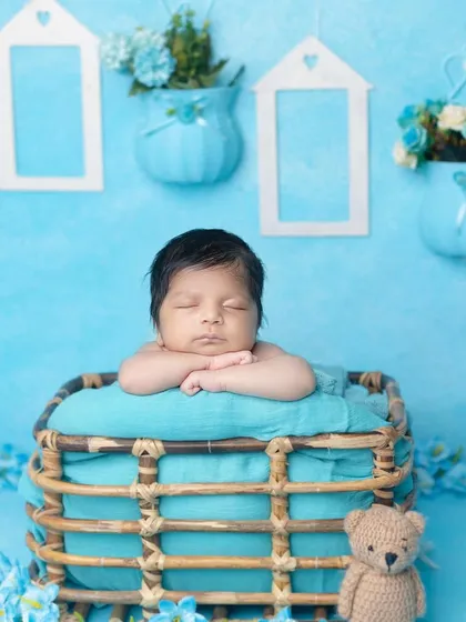A classic newborn pose in a basket, set against a beautiful blue backdrop.