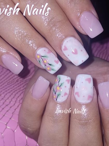 A soft and pretty set with light pink nails and accent nails featuring tiny hearts and a delicate floral branch.