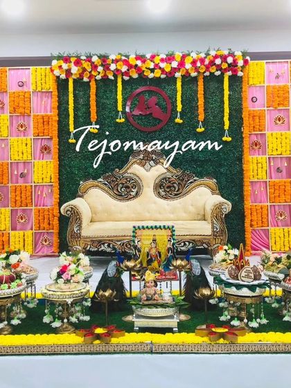 A baby shower setup with a pink and yellow marigold backdrop against a green wall, creating a beautiful contrast of colors.