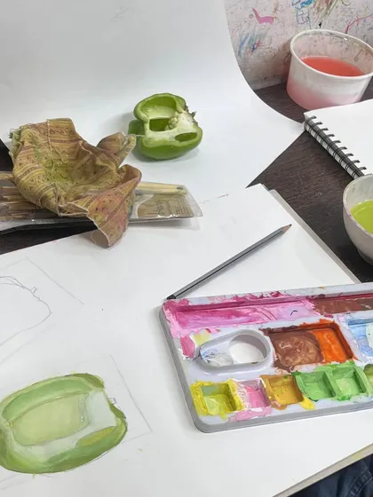 The artist's desk during a still life session. You can see the reference object, initial sketches, and the color palette used to bring the vegetable study to life on paper.