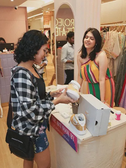 Here I am interacting with a customer at the Project Tete-a-Tete festive edit. She's checking out a pair of custom-painted sneakers at my pop-up, "The Art Nook by Ridhii Makkar."
