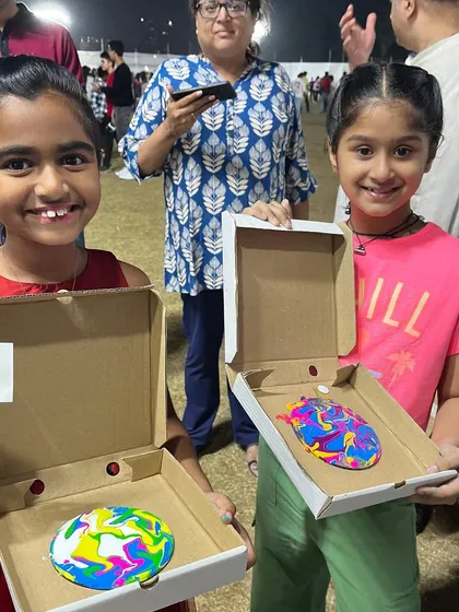 Two happy girls showing off the colorful fluid art coasters they created at my carnival booth. The unpredictable and beautiful results of paint pouring are always a delight.